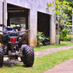 Úžitková štvorkolka pracujúca v rozľahlej záhrade s nástrojmi