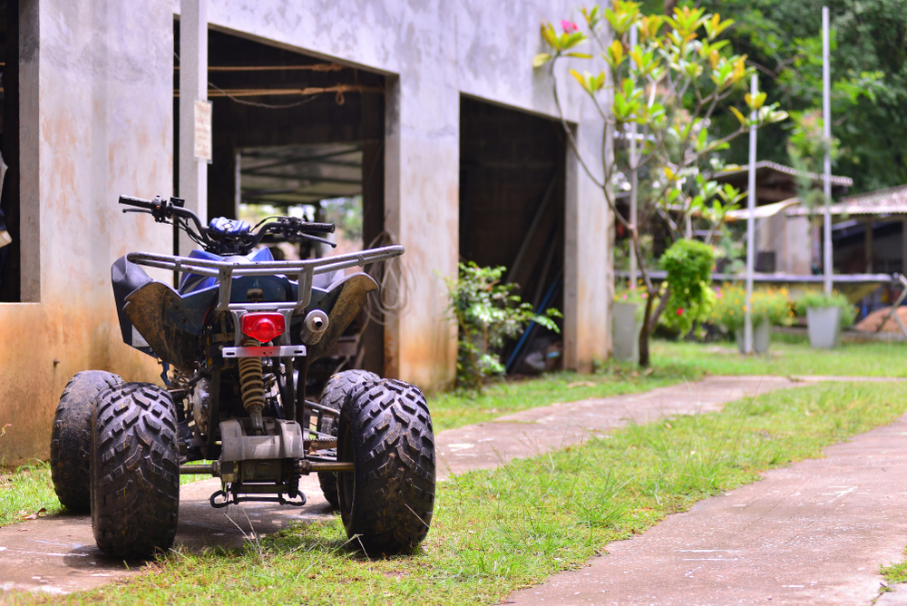 Úžitková štvorkolka pracujúca v rozľahlej záhrade s nástrojmi