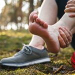 Turista v pohorí si upravuje obuv, aby predišiel pľuzgierom počas túry.