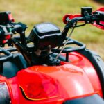 Detailný pohľad na riadidlá a prístrojový panel elektrickej štvorkolky zaparkovanej na tráve.