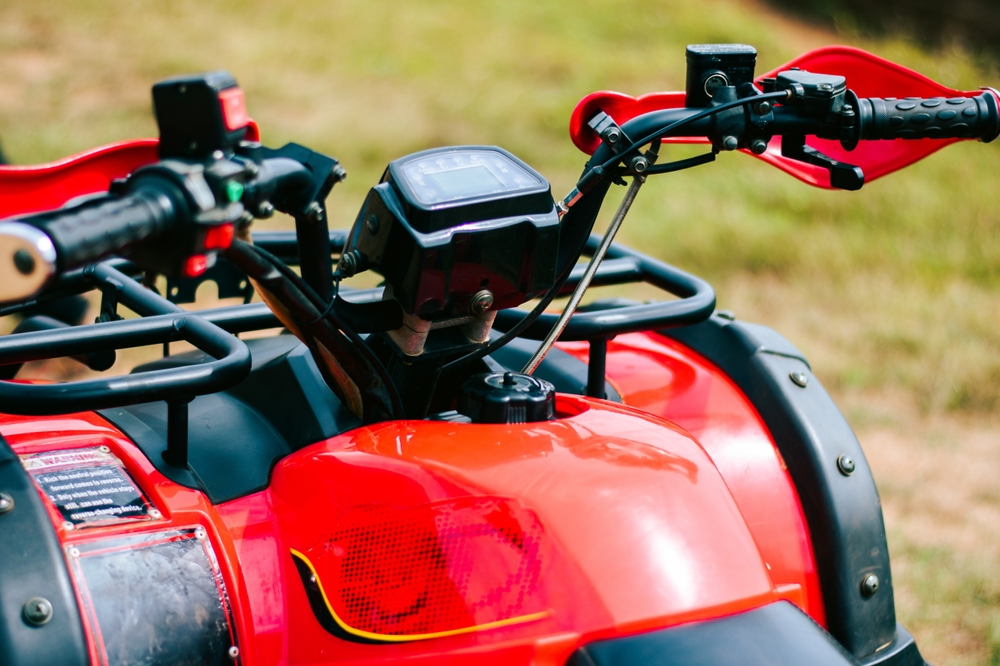 Detailný pohľad na riadidlá a prístrojový panel elektrickej štvorkolky zaparkovanej na tráve.