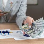 Podnikateľ počíta firemné náklady pri stole s kalkulačkou a šálkou kávy