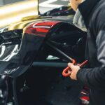 Detail karosérie auta s drobnou preliačinou po páde konára a náradím na jej opravu