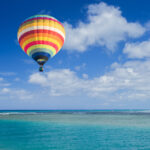 Farebný teplovzdušný balón stúpa nad slovenskou krajinou počas východu slnka