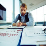 Podnikateľ vypĺňa dokumenty na registráciu predmetu podnikania pri stole.