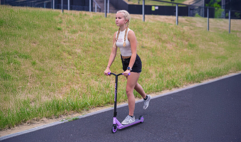 Dieťa jazdí na kolobežke na ihrisku a užíva si pohyb na čerstvom vzduchu.