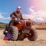Jazdec na Can-Am ATV s kompletnou ochrannou výbavou počas jazdy v teréne.