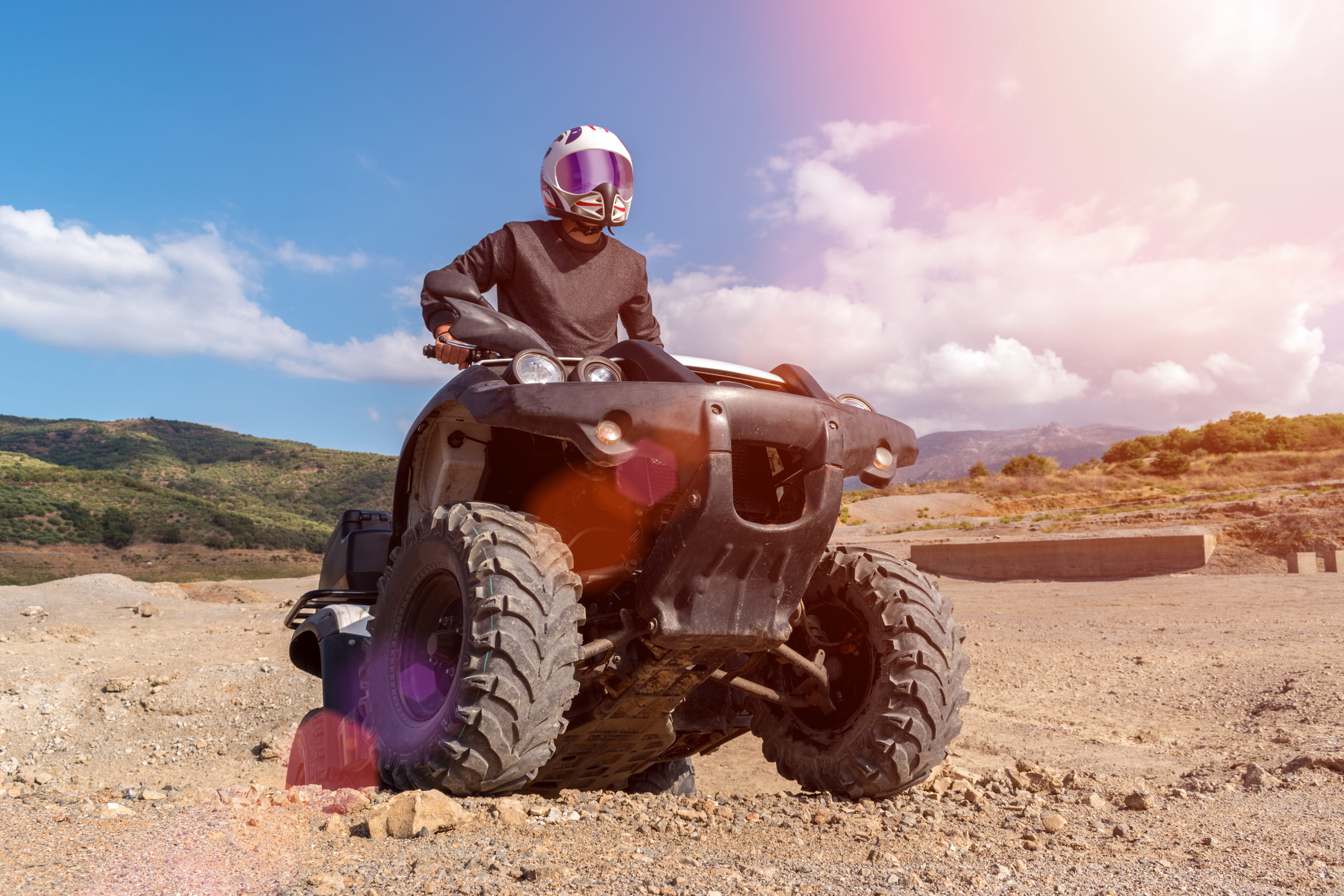 Jazdec na Can-Am ATV s kompletnou ochrannou výbavou počas jazdy v teréne.