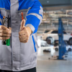 Automechanik kontrolujúci vozidlo v autoservise a zákazník preverujúci rozsah a cenu opravy automobilu.