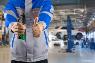 Automechanik kontrolujúci vozidlo v autoservise a zákazník preverujúci rozsah a cenu opravy automobilu.