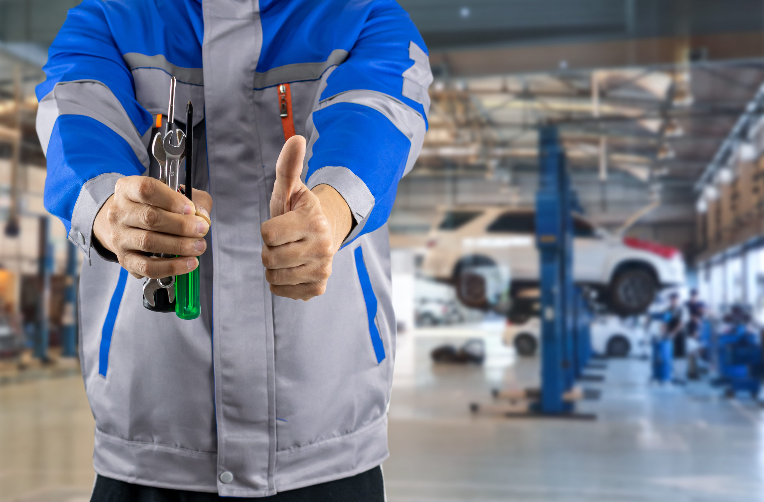 Automechanik kontrolujúci vozidlo v autoservise a zákazník preverujúci rozsah a cenu opravy automobilu.