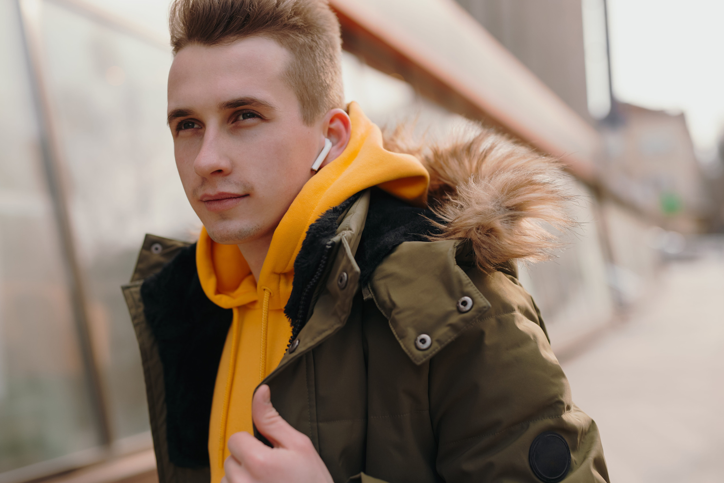 Muž v zimnej bunde kráča zasneženým mestom